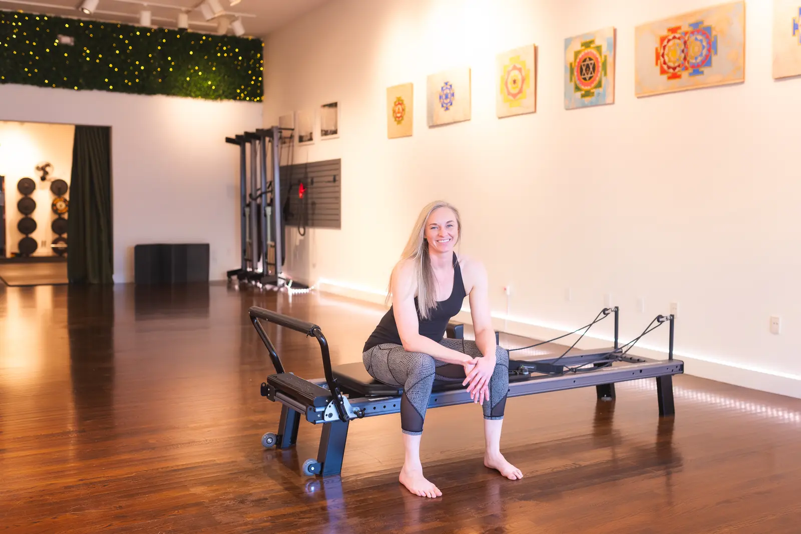 Allison sitting on a reformer in the studio.